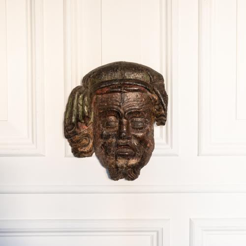 A rare Henry IV oak polychromed appliqué or mount, designed as a male mask, circa 1410